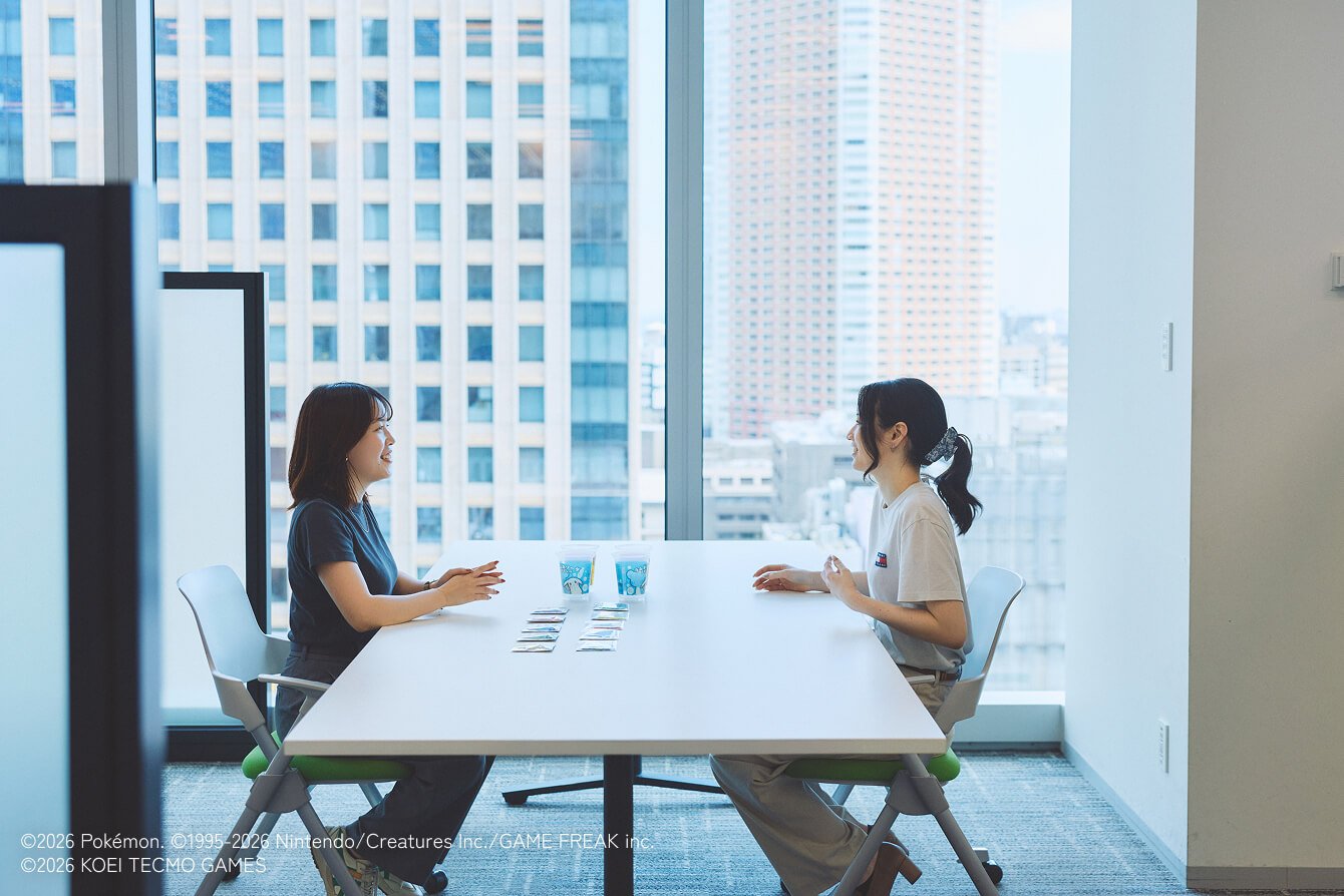 商品が並んだデスクを挟み向き合って話している様子