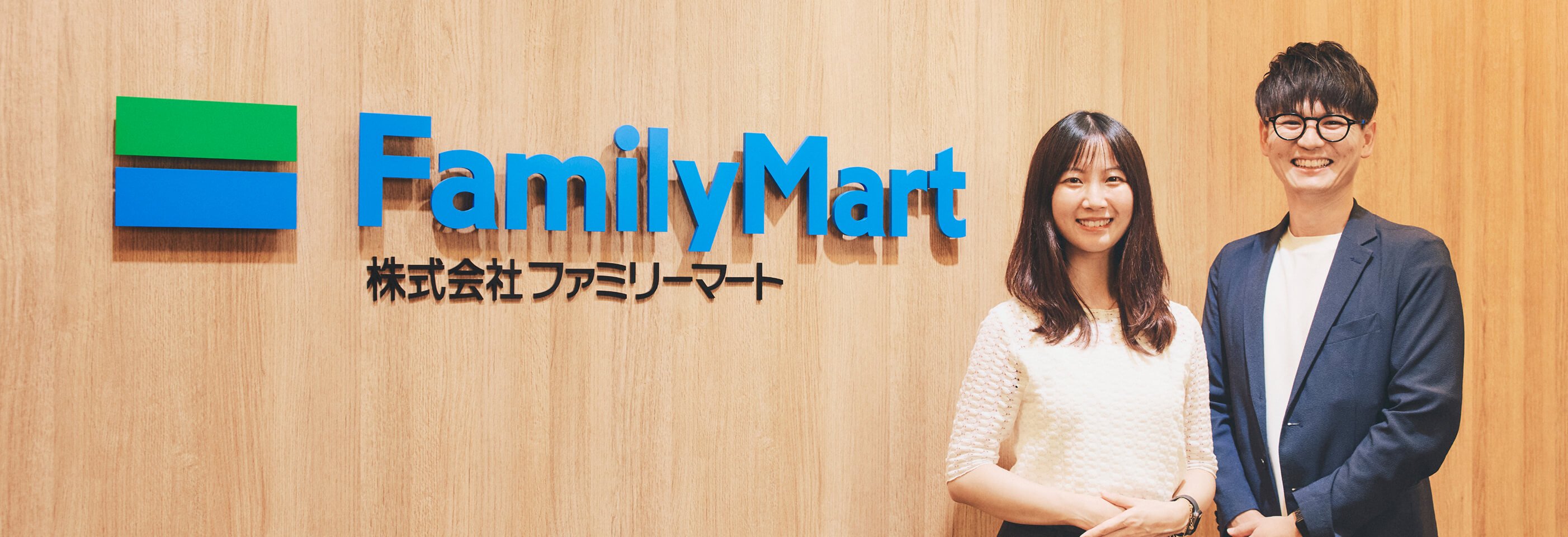 familymartのロゴを手のひらで指している男女の社員